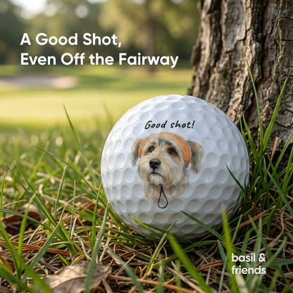 Custom dog golf ball lying in the rough grass next to a tree, showing the durable print quality for actual play on the golf course.